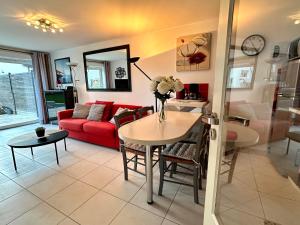 Una sala de estar con un sofá rojo y una mesa. en Holiday Home Joannie by Interhome, en Saint-Brevin-les-Pins