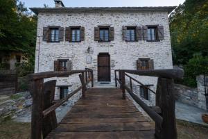 a wooden bridge leading to a stone building with a door at Archontiko Michael Pelion in Vyzitsa