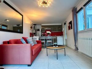 Una sala de estar con un sofá rojo y una mesa. en Holiday Home Joannie by Interhome, en Saint-Brevin-les-Pins