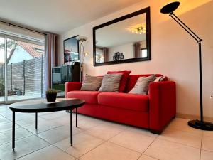 Un sofá rojo en una sala de estar con una mesa. en Holiday Home Joannie by Interhome, en Saint-Brevin-les-Pins 10 fotos más