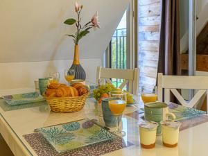 a table with a basket of bread and glasses of orange juice at Apartment Le Château de Kergonano-10 by Interhome in Baden