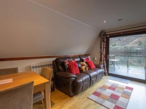 a living room with a brown leather couch with red pillows at Chalet Lodge 26 by Interhome in Spean Bridge