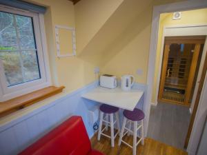 a small kitchen with a table and two stools at Chalet Cobbs by Interhome in Drumnadrochit