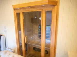 um armário de madeira com uma porta de vidro num quarto em Chalet Nessie 1 by Interhome em Drumnadrochit