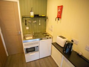 uma pequena cozinha com fogão e micro-ondas em Chalet Nessie 1 by Interhome em Drumnadrochit