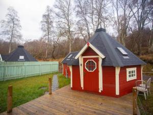 a red house with a black roof on a deck at Chalet Campbell by Interhome in Drumnadrochit