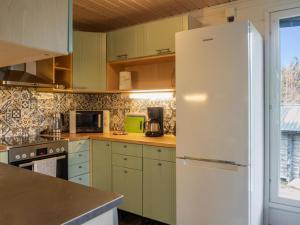 um frigorífico branco numa cozinha com armários verdes em Holiday Home Villa akonpuro by Interhome em Sotkamo
