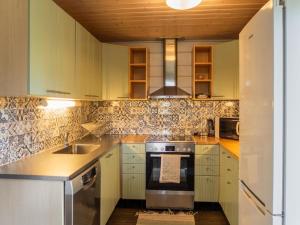a kitchen with white cabinets and a stove at Holiday Home Purontupa by Interhome in Sotkamo