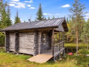a cabin in the woods with a wooden porch at Holiday Home Purontupa by Interhome in Sotkamo