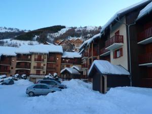 um parque de estacionamento coberto de neve ao lado de edifícios em Studio Valloire, 1 pièce, 4 personnes - FR-1-263-5 em Valloire