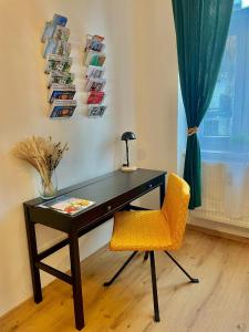 a desk with a yellow chair next to a window at JS Design Apartment in Graz