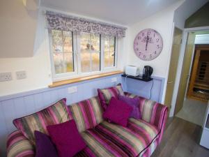a living room with a couch and a clock on the wall at Chalet Affric 3 by Interhome in Drumnadrochit