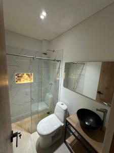 a bathroom with a toilet and a glass shower at Hotel La Casona San Sebastian in Doradal
