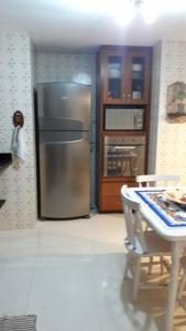 a kitchen with a stainless steel refrigerator and a table at Casa completa + área gourmet in Búzios
