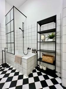 a bathroom with a white tub and a checkered floor at LE Vacation 3-Room-City-Apartment, Küche, Neflix, Free TV in Leipzig