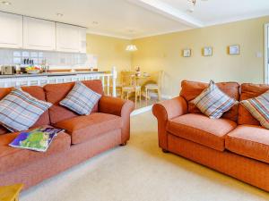 a living room with two couches and a kitchen at 1 Bed in Tenby 83320 in Tenby