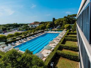 uma vista superior para uma piscina com cadeiras e guarda-sóis em Apartment Magnolia-12 by Interhome em Marina di Bibbona