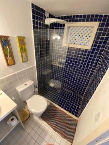 a bathroom with a toilet and a blue tiled shower at Peixe Crew Manguinhos in Búzios