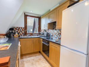 a kitchen with wooden cabinets and a white refrigerator at Chalet Lodge 4 by Interhome in Spean Bridge