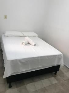 a white bed with two towels on top of it at Pousada Linhares in João Pessoa