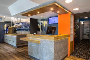 a bar in a restaurant with an orange wall at ibis budget Marne la Vallée Chelles in Chelles