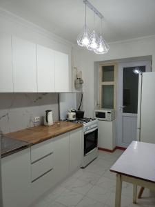 een keuken met witte kasten en een witte koelkast bij Трешка на Автовокзале in Qizilorda