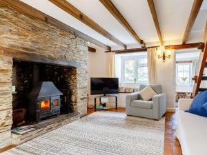 a living room with a stone fireplace and a chair at 2 bed property in Wadebridge 87231 in Egloshayle