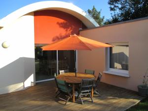 ル・コンケにあるHoliday Home Lochrist Le Conquetの木製テーブル(デッキ上のオレンジの傘付)
