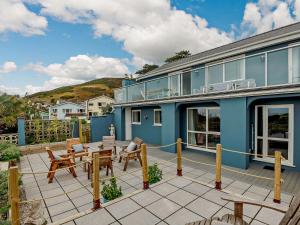 a blue house with a patio with tables and chairs at 4 Bed in Aberdovey 86911 in Aberdyfi