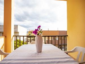 un jarrón con flores púrpuras sentado en una mesa en un balcón en Apartment Tanca Torre 60P by Interhome, en Trinità dʼAgultu