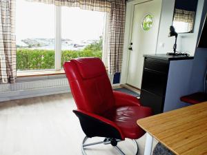 une chaise rouge dans une chambre avec une table et une fenêtre dans l'établissement Holiday Home Utsikten - OEL100 by Interhome, à Byxelkrok