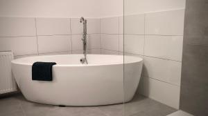 uma banheira branca na casa de banho com uma toalha preta em Schneiders Ferienwohnung 2 em Braunshausen