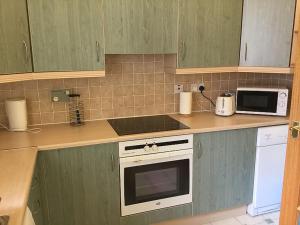 una cocina con armarios verdes y una estufa blanca en Apartment Old Edinburgh Cottage by Interhome en Inverness
