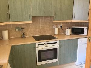 a kitchen with green cabinets and a white stove top oven at Apartment Old Edinburgh Cottage by Interhome in Inverness