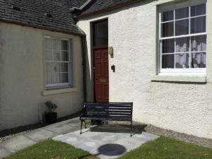 a black bench sitting in front of a house at Apartment Old Edinburgh Cottage by Interhome in Inverness