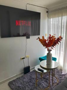 una sala de estar con una mesa con un jarrón de flores en Acogedor apartamento en Barrancabermeja, en Barrancabermeja