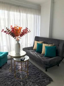 a living room with a couch and a table with a vase at Acogedor apartamento en Barrancabermeja in Barrancabermeja