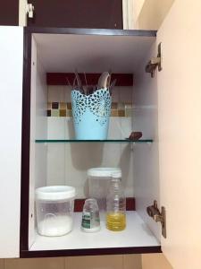 a cabinet with a shelf with containers and a blue pot at Acogedor apartamento en Barrancabermeja in Barrancabermeja