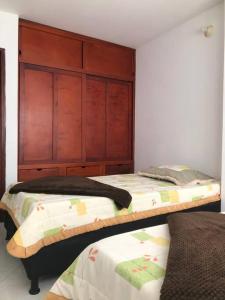 a bedroom with two beds and a wooden headboard at Acogedor apartamento en Barrancabermeja in Barrancabermeja