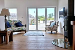 a living room with a couch and chairs and a sliding glass door at Rural Cornish Cottage in Truro