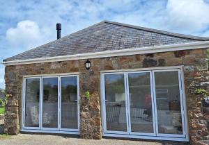 a stone house with sliding glass doors at Rural Cornish Cottage in Truro