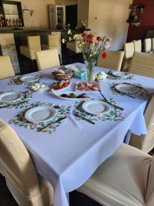 a white table with plates and flowers on it at Hotel Kos in Kosobudz