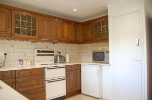 una cocina con armarios de madera y electrodomésticos blancos en Hafan Y Talgarth bungalow at Plas Talgarth resort, en Pennal