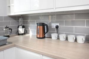 an orange coffee pot on a kitchen counter with white cups at Executive 8 Beds 2 Bath Home Contractors Parking in Southampton