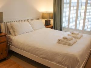 ein Schlafzimmer mit einem weißen Bett und Handtüchern darauf in der Unterkunft Cindy's Retreat in Hope-Cove