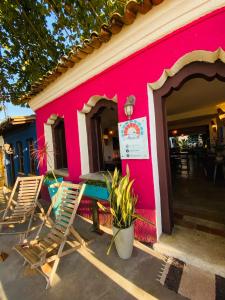 a pink building with chairs and a table outside at Pousada Anacã in Arraial d'Ajuda