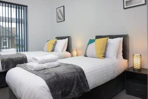 1 Schlafzimmer mit 2 Betten mit weißen und gelben Kissen in der Unterkunft Exclusive 8beds 2bath Luxury Contractors Delight! in Southampton