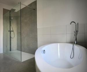 La salle de bains est pourvue d'une baignoire blanche et d'une douche. dans l'établissement Schneiders Ferienwohnung 1, à Braunshausen