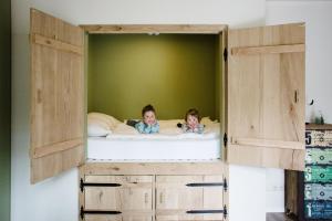 zwei Kinder auf einem Etagenbett in einem Schlafzimmer in der Unterkunft Groepsaccommodatie / Familiehuis Bolle Buik, Borrel & Bed Appelscha in Appelscha