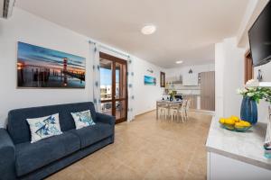 a living room with a blue couch and a kitchen at I Tre Golfi - Via Salvatore Quasimodo in San Vito lo Capo